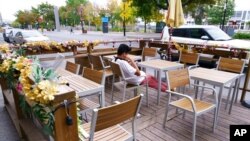 FILE - A person sits at an outdoor table in Montreal, Sept. 28, 2020. 