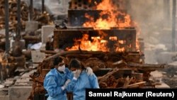 Anggota keluarga Vijay Raju, yang meninggal karena COVID-19, berkabung sebelum dikremasi di tempat krematorium di desa Giddenahalli di pinggiran Bengaluru, India, 13 Mei 2021. (Foto: REUTERS/Samuel Rajkumar)