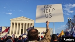 FILE: A person holds a sign during a rally to protest the results of the election, in front of the U.S. Supreme Court, in Washington, Dec. 12, 2020. 