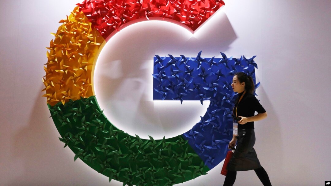 In this Monday, Nov. 5, 2018 file photo, a woman walks past the logo for Google at the China International Import Expo in Shanghai. (AP Photo/Ng Han Guan, File)
