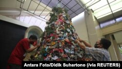 Sejumlah pria mendekorasi pohon Natal dengan masker dan penyanitasi tangan di sebuah gereja di Surabaya, Jawa Timur, 16 Desember 2020. (Foto: Antara Foto/Didik Suhartono via Reuters)