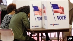 FILE - Voters fill out their ballots in the kiosks in Jackson, Miss., March 10, 2020.