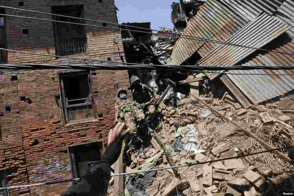 A Nepalese army soldier descends from a mound of rubble during the recovery of a body in the aftermath of Saturday&#39;s earthquake in Bhaktapur, Nepal.