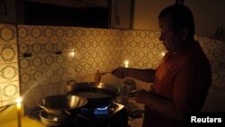 A man cooks near lit candles at his home during a power cut in San Cristobal, in the state of Tachira, Venezuela, April 25, 2016