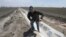 FILE - Farmer Gino Celli climbs out of a irrigation canal that is covered in dried salt on a field he farms near Stockton, Calif., May 18, 2015.