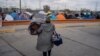 En esta foto de archivo una mujer lleva sus pertenencias a una parte diferente del campamento cerca de los puertos de entrada de Estados Unidos en Chamizal el 19 de diciembre de 2019 en Ciudad Juárez, México.