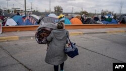 En esta foto de archivo una mujer lleva sus pertenencias a una parte diferente del campamento cerca de los puertos de entrada de Estados Unidos en Chamizal el 19 de diciembre de 2019 en Ciudad Juárez, México.