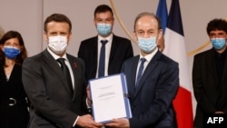 Le président français Emmanuel Macron détient conjointement un document aux côtés de l'historien Vincent Duclert, qui dirige la commission rwandaise à la salle des fêtes de l'Elysée à Paris, le 26 mars 2021.