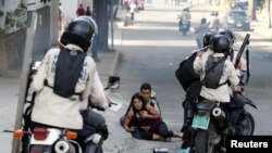 FILE - Opposition supporters affected by tear gas react next to members of the security forces during a rally against Venezuelan President Nicolas Maduro's government in Caracas, Venezuela, July 9, 2017. 