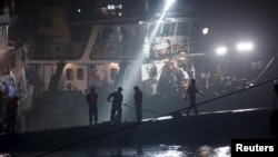 Rescue workers are seen atop the sunken ship in the Jianli section of Yangtze River, Hubei province, China, June 3, 2015. 