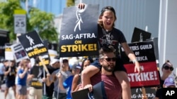 ARCHIVO - El director de fotografía Jac Cheairs y su hijo, el actor Wyatt Cheairs, de 11 años, participan en una manifestación de guionistas y actores en huelga frente al estudio de Netflix en Los Ángeles el 14 de julio de 2023.