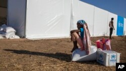 FILE - A Tigray refugee girl who fled the conflict in Ethiopia's Tigray region, sits on aid she received from the UNHCR and WFP at Umm Rakouba refugee camp on the Ethiopia-Sudan border, Nov. 24, 2020.