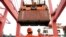 FILE - An employee guides as a crane unloads shipping containers from a cargo ship at a port in Lianyungang, Jiangsu province, China.