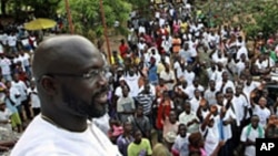 FILE - George Weah, a former soccer star and the running mate of presidential candidate Winston Tubman of the Congress for Democratic Change (CDC), stands at the balcony after a news conference at his headquarters in Monrovia, November 5, 2011.