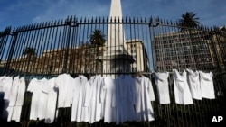 FILE - White medical coats hanging from the iron gate that surrounds the national monument May Pyramid, as a symbolic act against efforts to legalize abortion, in Buenos Aires, Argentina, July 15, 2018.