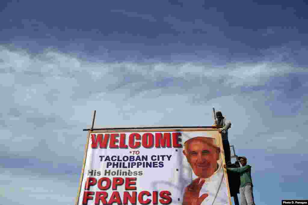 Workers hang a banner welcoming Pope Francis to Tacloban, Jan. 15, 2015.