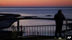 A local resident watches the coast from Hiyoriyama Park after a tsunami warning was issued for coastal towns in northeastern Japan in this photo taken by Kyodo on Jan. 16, 2022. 