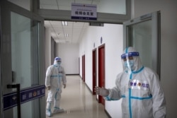 FILE - Security officers in protective suits stand in a hallway with rooms for video meetings with inmates at the visitors' hall at the Urumqi No. 3 Detention Center in Dabancheng in western China's Xinjiang Uyghur Autonomous Region, April 23, 2021.