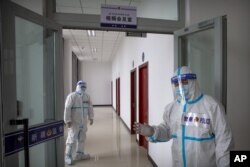 FILE - Security officers in protective suits stand in a hallway with rooms for video meetings with inmates at the visitors' hall at the Urumqi No. 3 Detention Center in Dabancheng in western China's Xinjiang Uyghur Autonomous Region, April 23, 2021.