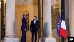 United States Special Presidential Envoy for Climate John Kerry, who traveled to Paris to relaunch transatlantic cooperation with European officials, speaks with France's President Emmanuel Macron after a meeting, March 10, 2021,