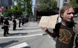 FILE - A man holds a sign that reads "Q-Nited We Stand" during a rally held by members of Patriot Prayer and other groups supporting gun rights near City Hall in Seattle.