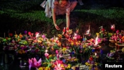 A woman places a Krathong, a floating basket made with leaves and flowers, into a park&#39;s lagoon during the Loy Krathong festival, a symbolic apology and expression of gratitude to the goddess of the river for the water, in Bangkok, Thailand. REUTERS/Chalinee Thirasupa