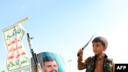 FILE - A Yemeni child hold a knife next to a portrait of Huthi leader Abdul Malik al-Houthi during a march in solidarity with the people of Gaza in the Huthi-controlled capital Sanaa on January 5, 2024 amid the ongoing battles between Israel and Hamas in Gaza.