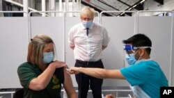 Britain's Prime Minister Boris Johnson watches first responder Caroline Cook receiving an injection of a COVID-19 vaccine at Ashton Gate Stadium in Bristol, England, Jan. 11, 2021. 