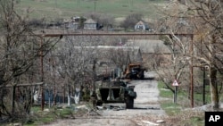 A damaged armed vehicle of pro-Russian rebels stands between the positions of the rebels and the Ukrainian army in Shyrokyne village, eastern Ukraine, April 10, 2015.