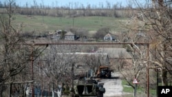 A damaged armed vehicle of pro-Russian rebels stands between the positions of pro-Russian rebels and Ukrainian army in Shyrokyne village, eastern Ukraine, April 10, 2015.