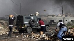 Des palestiniens jettent des pierres sur un véhicule de la police frontalière israélienne dans le village de Kfar Kadum, en Cisjordanie, près de Naplouse, le 25 janvier 2013. 