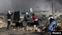 Des Palestiniens jettent des pierres sur un véhicule de la police israélienne près de la colonie juive de Kdumim, dans le village de Kfar Kadum, 25 janvier 2013.