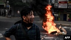A protester with his face painted stands near a burning makeshift barricade during a protest against the military coup, in Yangon, March 30, 2021. (AFP)