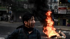 A protester with his face painted stands near a burning makeshift barricade during a protest against the military coup, in Yangon, March 30, 2021. (AFP)