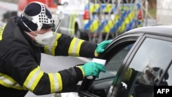 A Czech special police officer, with a protective mask, checks the temperature of a driver during sanitary checks at the border crossing between Germany and Czech Republic, in a measure to protect against the spread of the coronavirus, March 9, 2020.