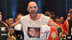 Champion du monde de la Grande-Bretagne, Tyson Fury, brandit les ceintures WBA, IBF, WBO et IBO remportées en battant Wladimir Klitschko de l'Ukraine lors d’un combat pour le titre des poids lourds à Düsseldorf, Allemagne de l'Ouest, 29 novembre 2015. 