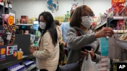 People wear protective face masks as they make purchases from a convenience store in Hong Kong, Monday, Feb, 3, 2020. 