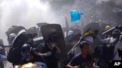 FILE - Protesters are dispersed as riot police fire tear gas during a demonstration in Yangon, Myanmar, March 8, 2021.