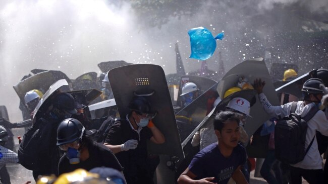 FILE - Protesters are dispersed as riot police fire tear gas during a demonstration in Yangon, Myanmar, March 8, 2021.
