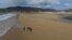 A woman walks her dogs along Dooagh beach after a storm returned sand to it, 30 years after another storm had stripped all the sand off the beach, on Achill island, County Mayo, Ireland, May 5, 2017. (Sean Molloy/Achill Tourism via Reuters) 
