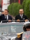 Morocco's King Mohammed VI, right, and French President Emmanuel Macron wave to crowds during the latter's official visit to Morocco, in Rabat, Oct. 28, 2024.