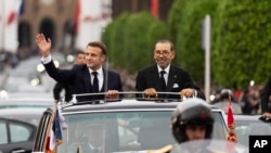 Morocco's King Mohammed VI, right, and French President Emmanuel Macron wave to crowds during the latter's official visit to Morocco, in Rabat, Oct. 28, 2024.