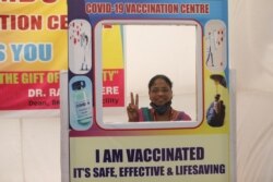 A woman poses for a picture with a cardboard cutout after receiving a dose of COVISHIELD, a COVID-19 vaccine manufactured by Serum Institute of India, Mumbai, India, March 1, 2021.