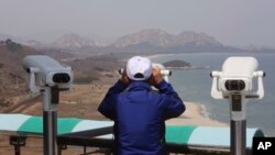 A South Korean tourist uses binocular to look at the Diamond Mountain in North Korea from the Unification Observation post in Goseong, South Korea, April 7, 2017.