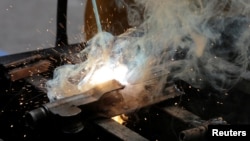 FILE - A Mexican soldier uses a welding torch to destroy weapons seized from alleged drug traffickers or handed in by residents at a military zone in Mexico City, Mexico.