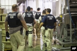FILE - Immigration and Customs Enforcement (ICE) together with Homeland Security Investigations (HSI) officers prepare to make arrests at an agricultural processing facility in Canton, Mississippi, Aug. 7, 2019.