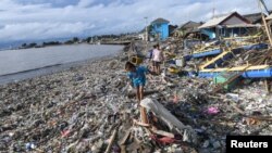 Warga berjalan di antara puing-puing setelah tsunami menerjang Labuan di Pandeglang, Provinsi Banten, 26 Desember 2018. (Foto: Antara via Reuters)