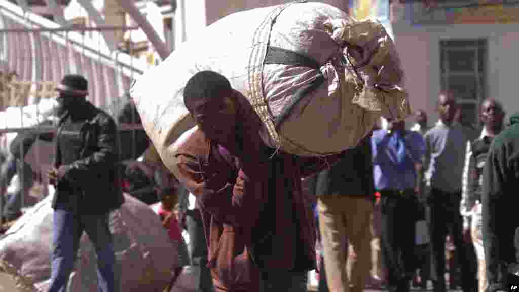 A vendor carries his goods after he was evicted from the streets by Zimbabwean police in Harare, Wednesday, July, 8, 2015. Minor scuffles ensued as police officers drove out thousands of vendors selling their wares on the sidewalks and pavements of Harare.