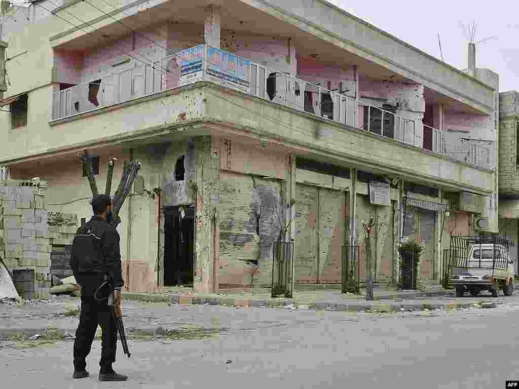 A Syrian rebel stands guard in front of a damaged building, Khaldiyeh, Homs, March 25, 2012. (AP) 