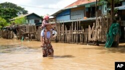 A women and child wade through a flooded road, in Naypyitaw, Myanmar, Sept. 17, 2024.